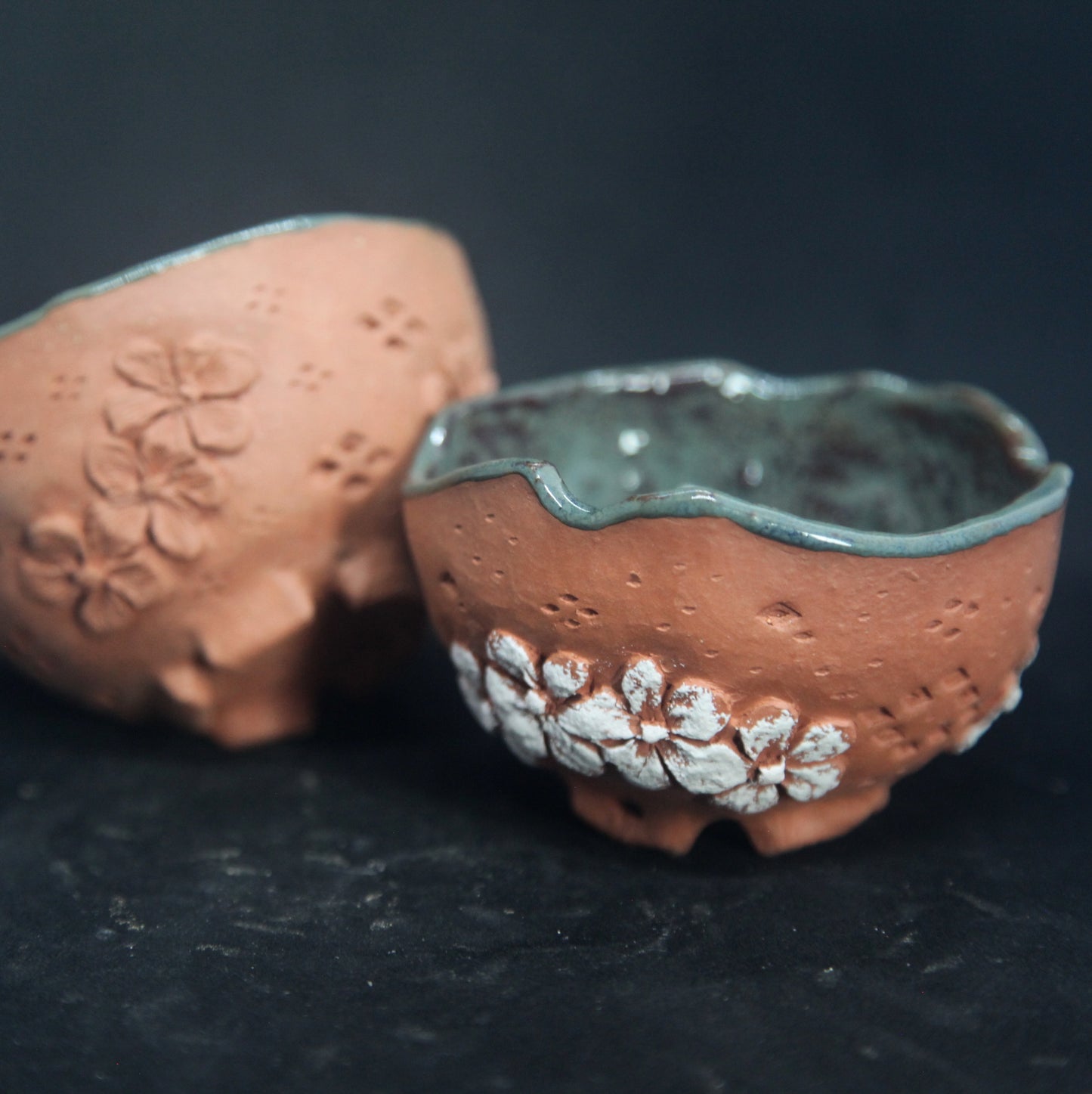 Tasses vert foncé sur terre rouge - motifs de fleurs