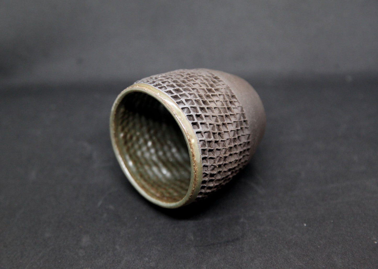 Green mug on black clay - twisted pattern