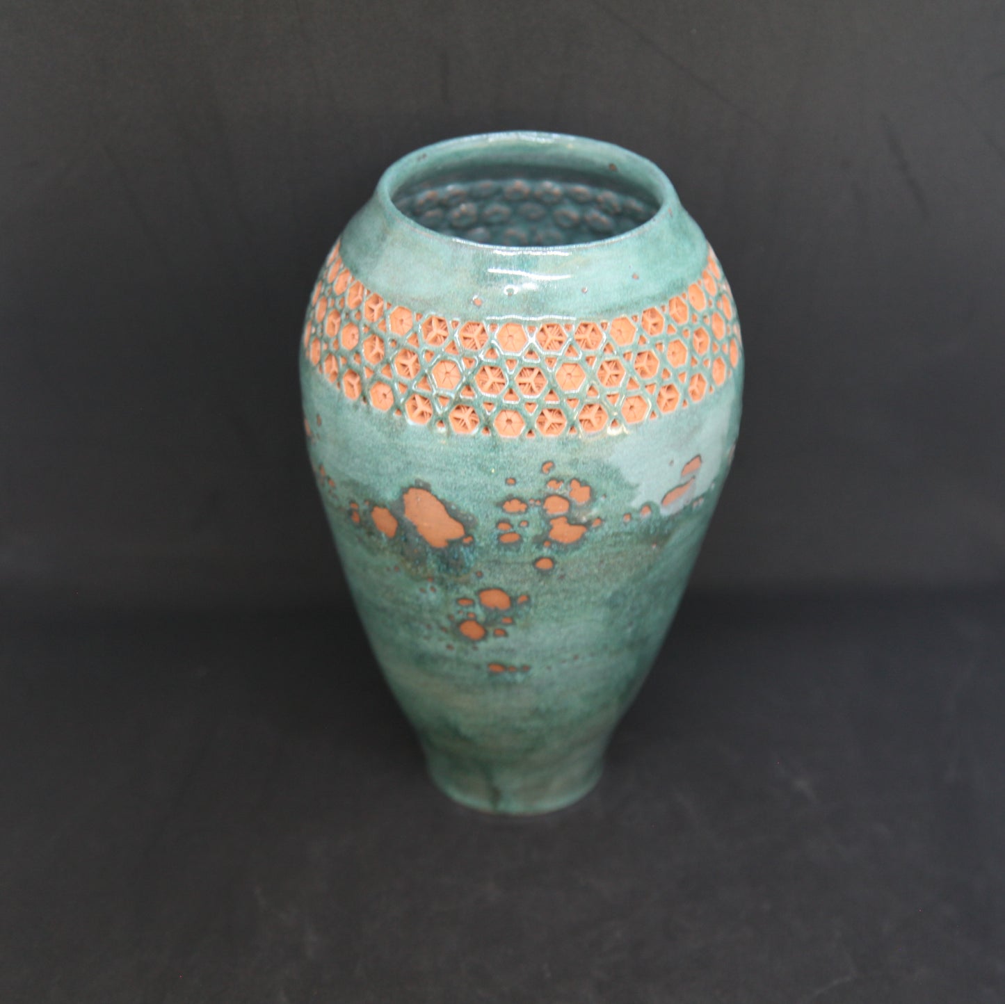 Green vase on red clay - origami pattern