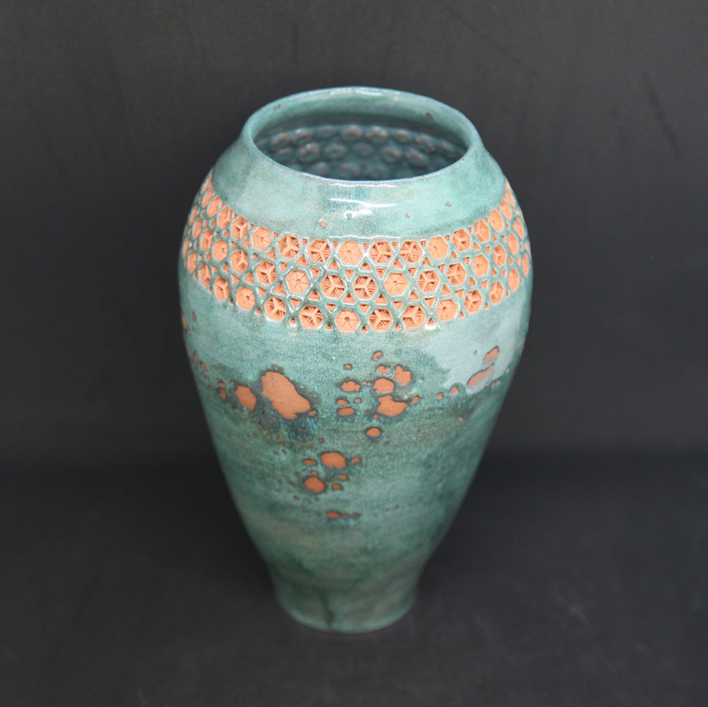 Green vase on red clay - origami pattern