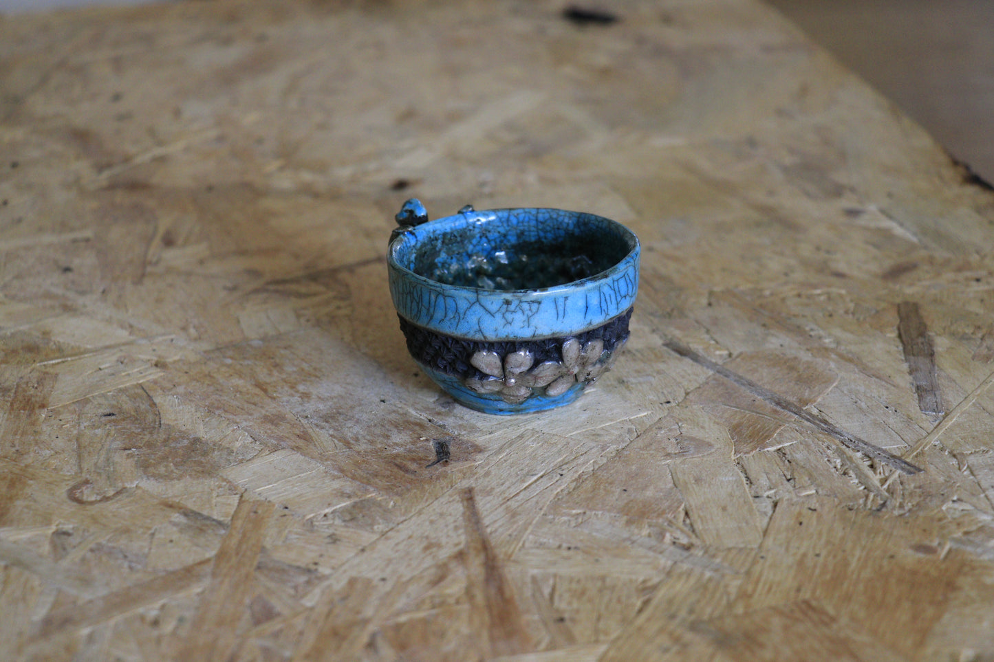 Tasse raku turquoise et noire, avec personnage