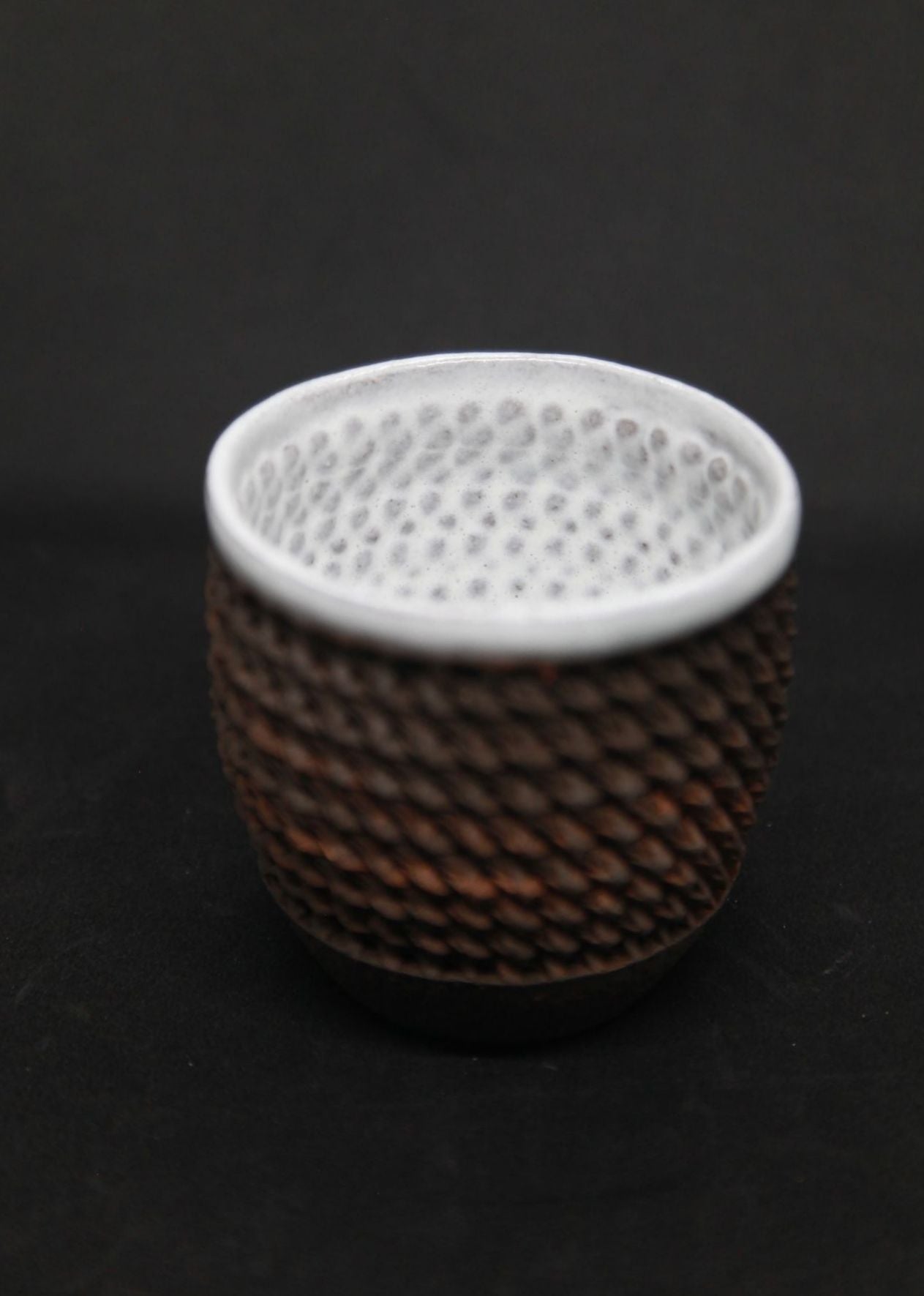 White mug on black clay - braiding pattern