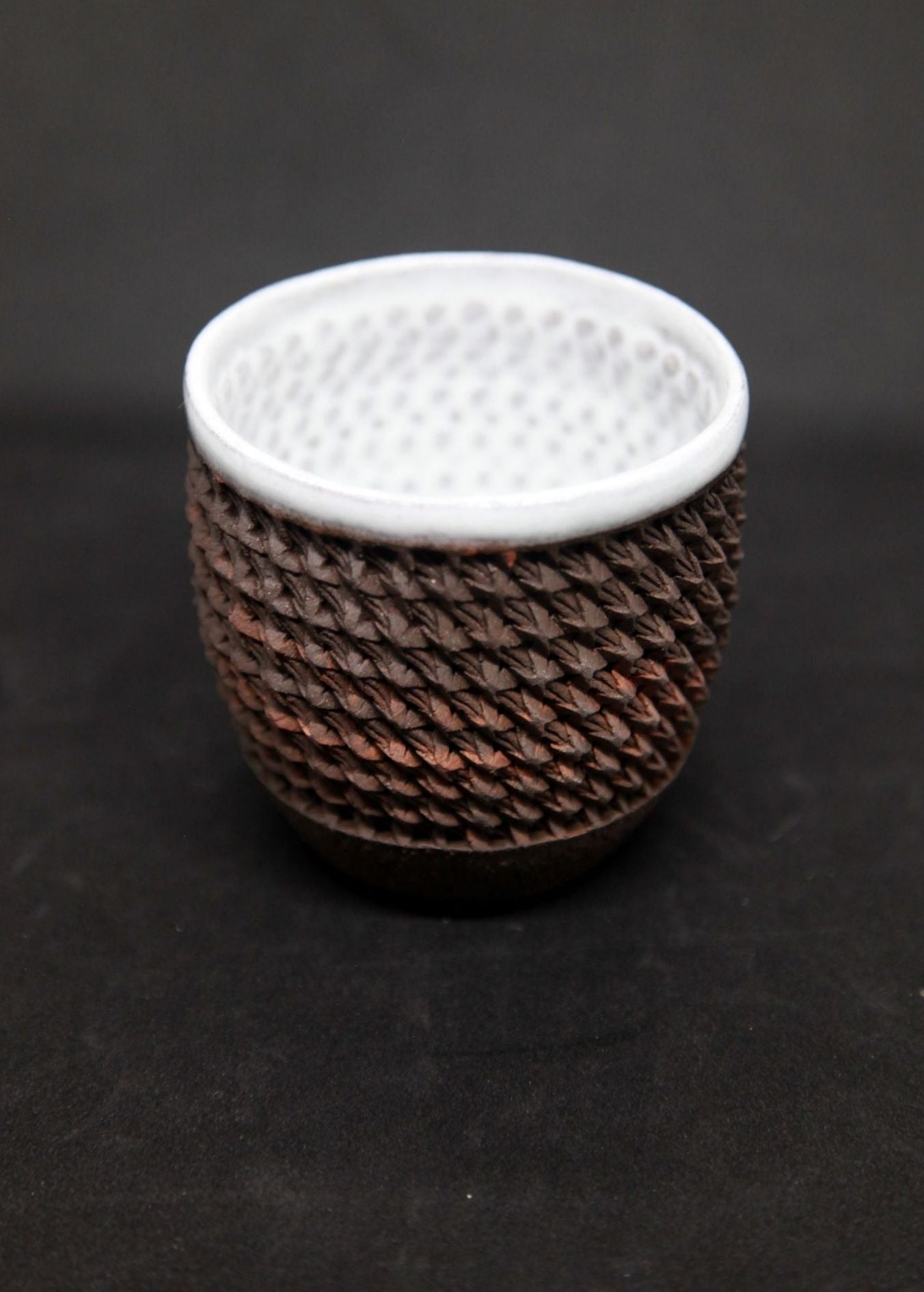 White mug on black clay - braiding pattern