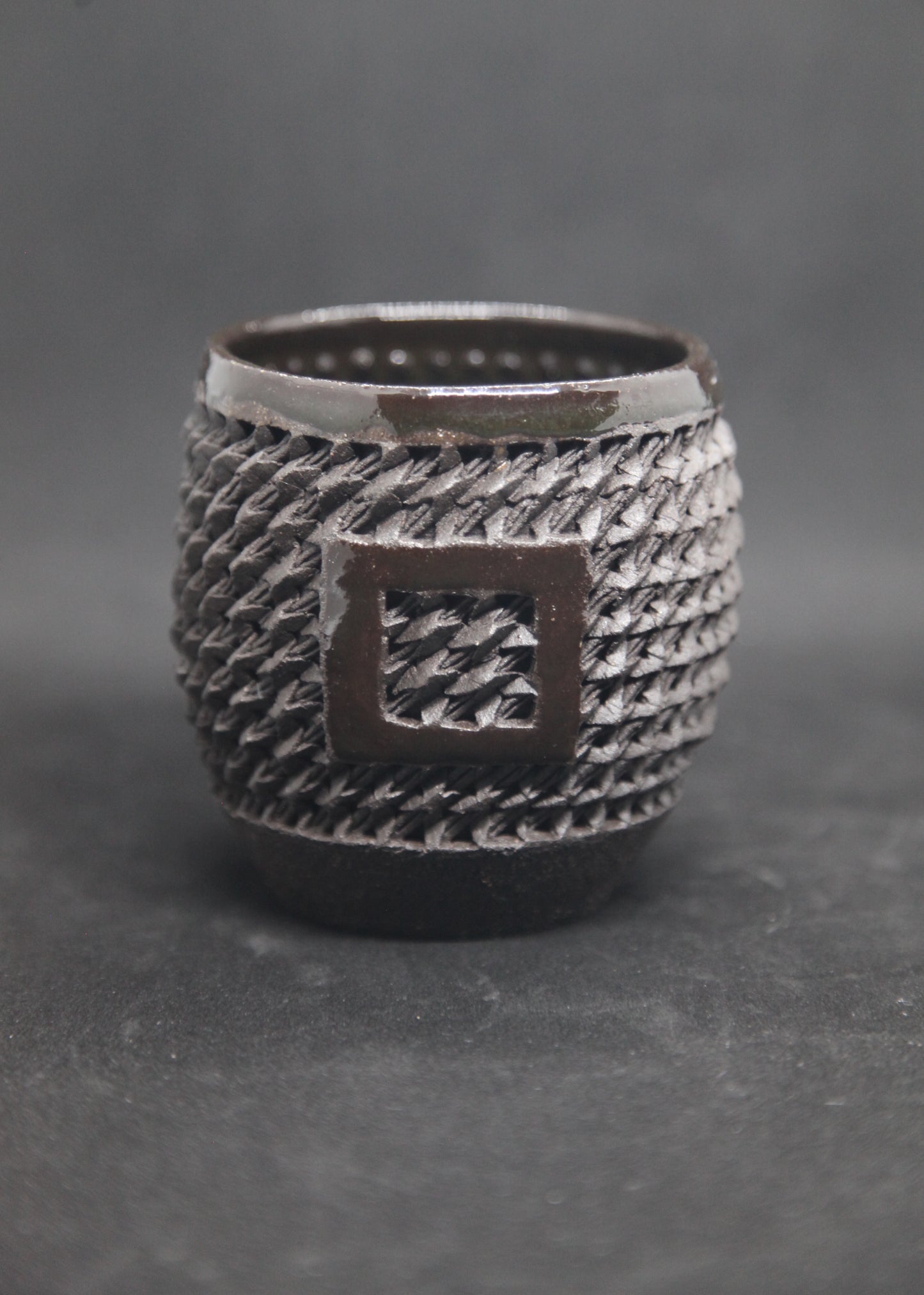 Black mug on black clay - braiding pattern
